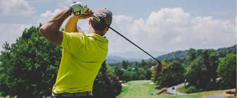 mann som slår et golfslag, sett bakfra. foto.